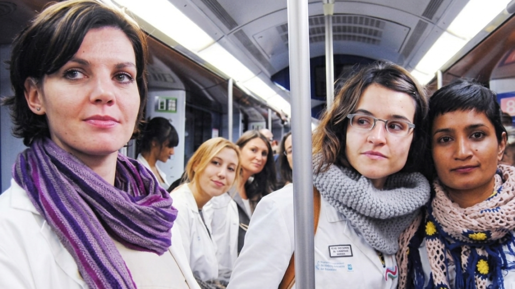 En grupp kvinnliga i vita rockar ombord på en tunnelbanevagn i Madrid under en protest mot privatiseringar av vården.